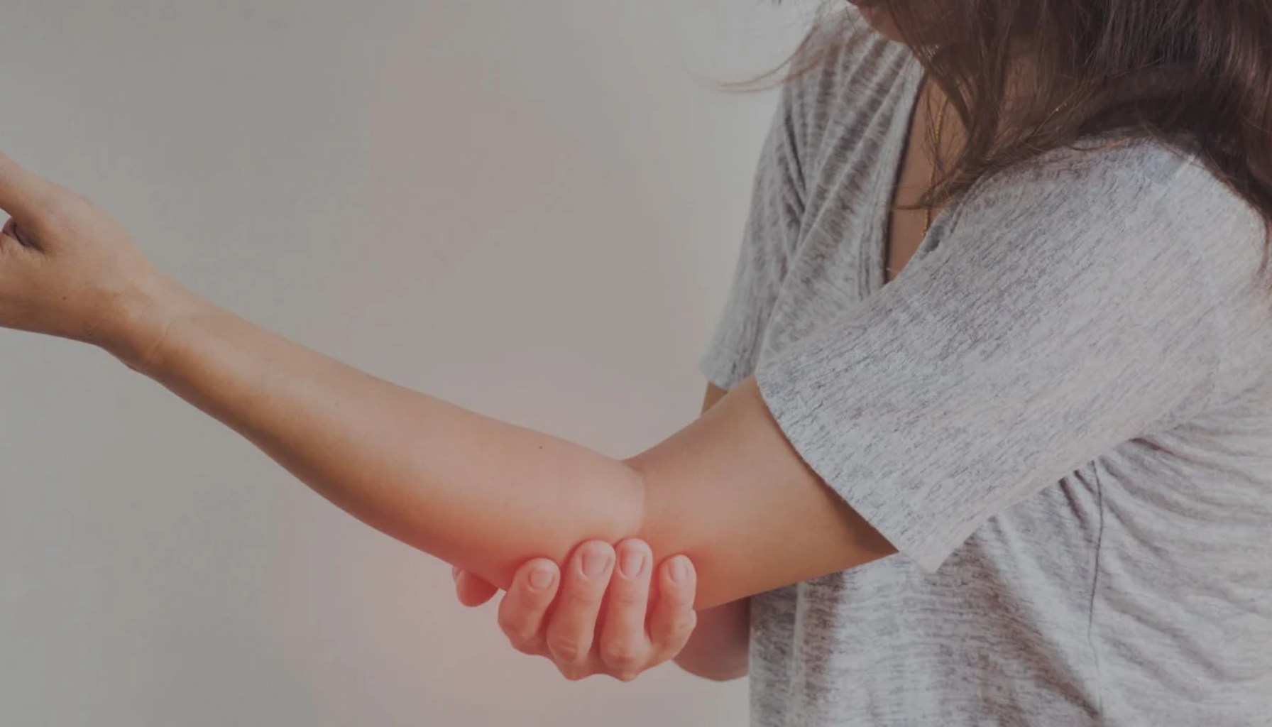 Kvinne holder seg til albuen med smerter, typisk ved nerver i klem og radikulopati.