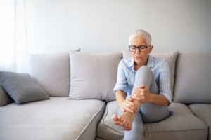 An image of a woman with rheumatoid arthritis holding her leg in pain. 