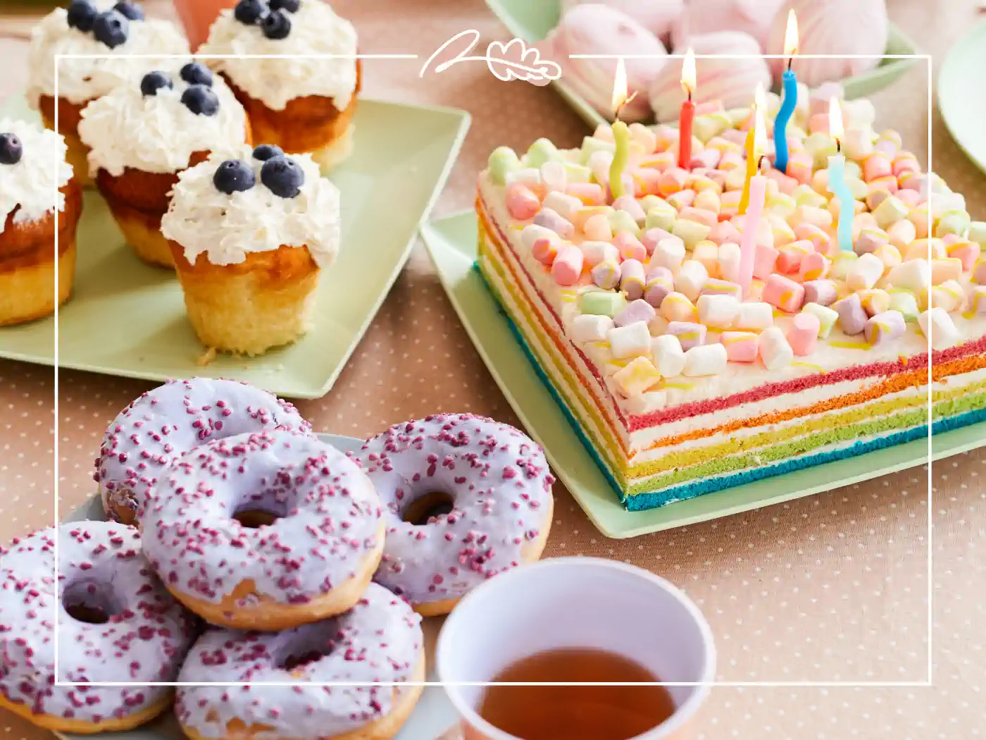 A variety of desserts including donuts, cupcakes with blueberries, and a rainbow-layered cake with candles. Fabulous Flowers and Gifts - Birthday Collection.