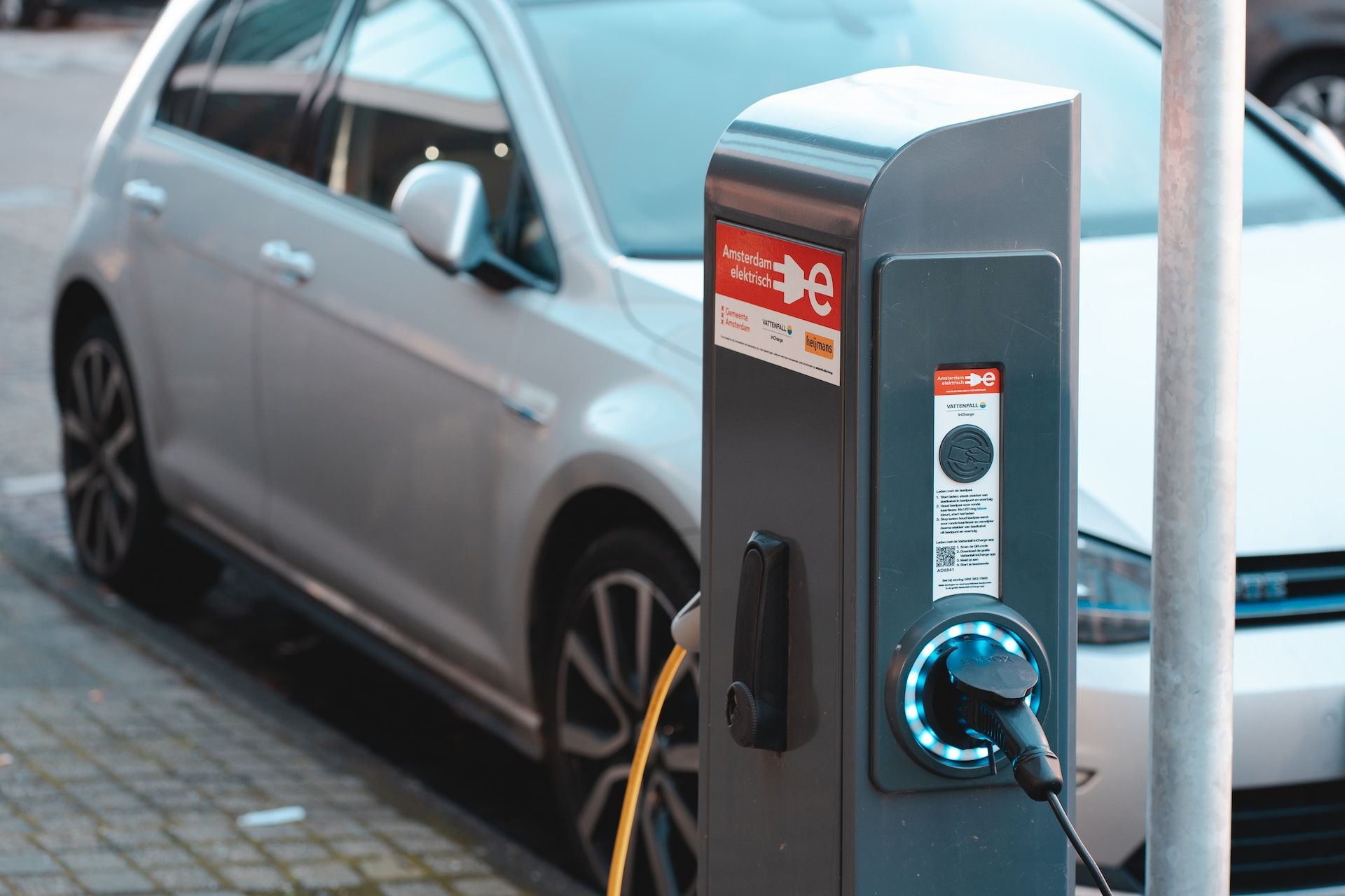 A man plugging a charging cable into a car's charging port