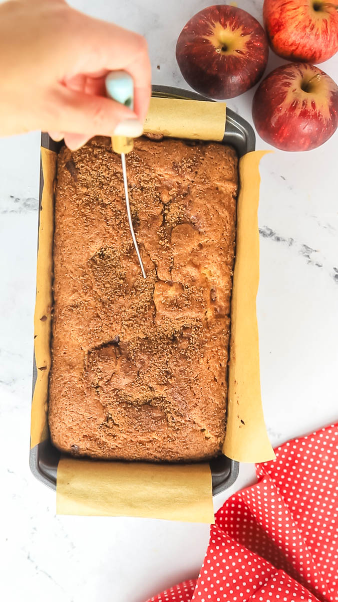 baked apple cinnamon bread in loaf pan tested with a toothpick