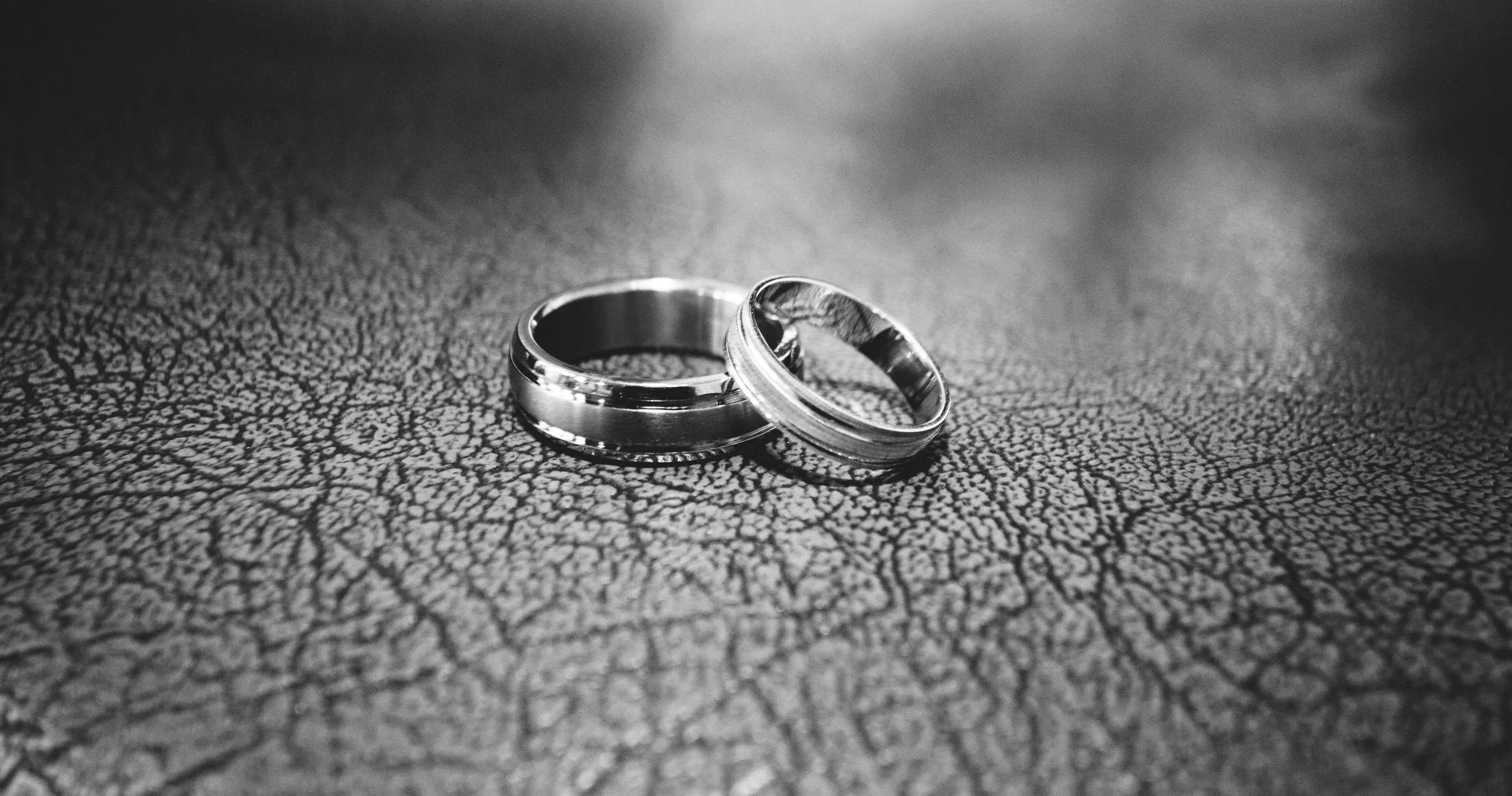 Two titanium rings, with one slightly above the other, displayed on a textured leather surface.