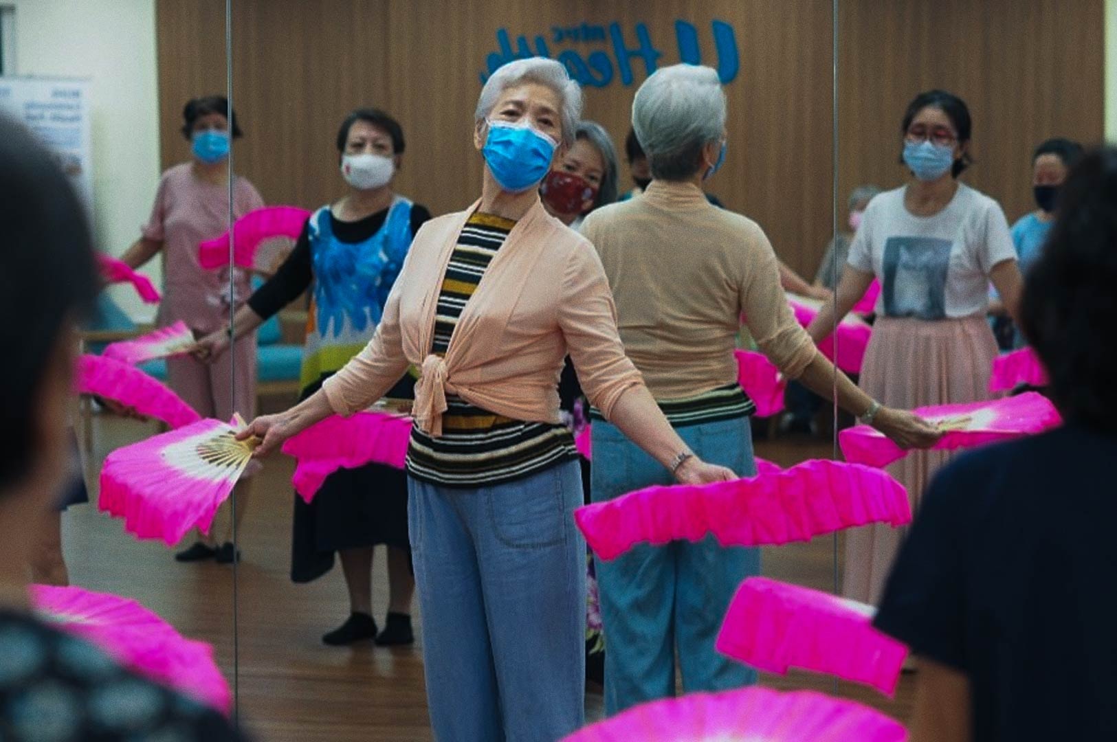 Seniors practicing a traditional fan dance routine in a mirrored studio.