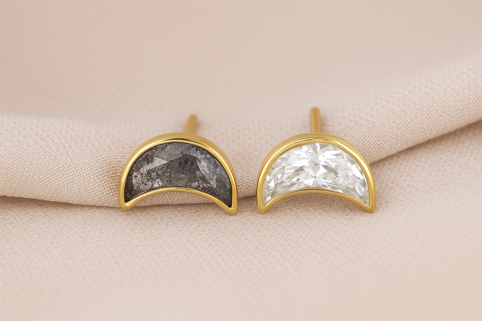 Earrings with crescent-shaped diamonds — one with salt and pepper, the other with a colorless diamond