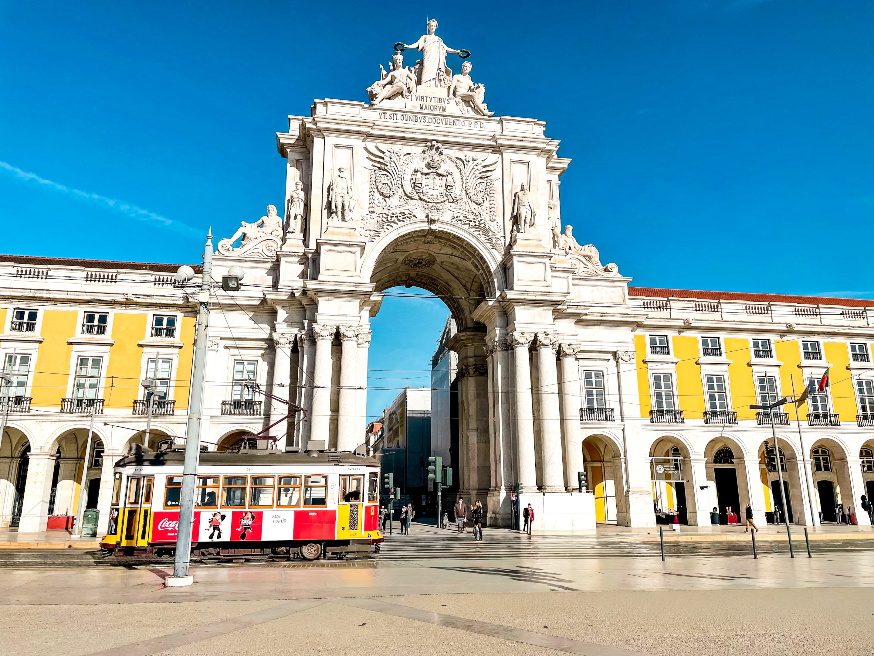 Where to stay in Lisbon Praça do Comércio with a colorful tram car in front on a sunny day in Lisbon, Portugal