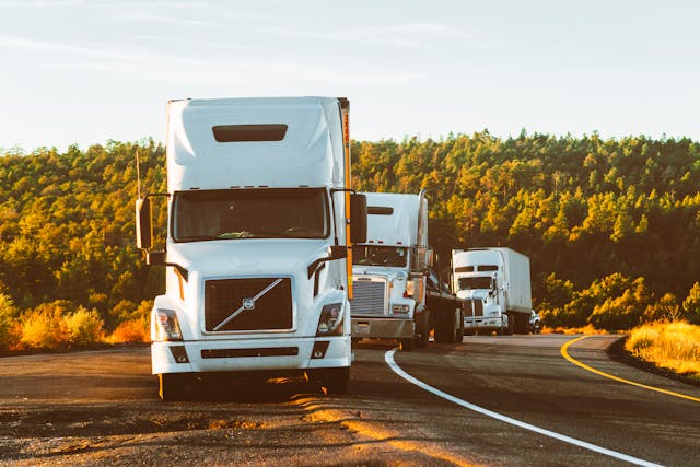 A photo of trucks driving in a row; Fleet managers need to track assets and make sure to reduce the number of unused vehicles for an optimal fleet usage.