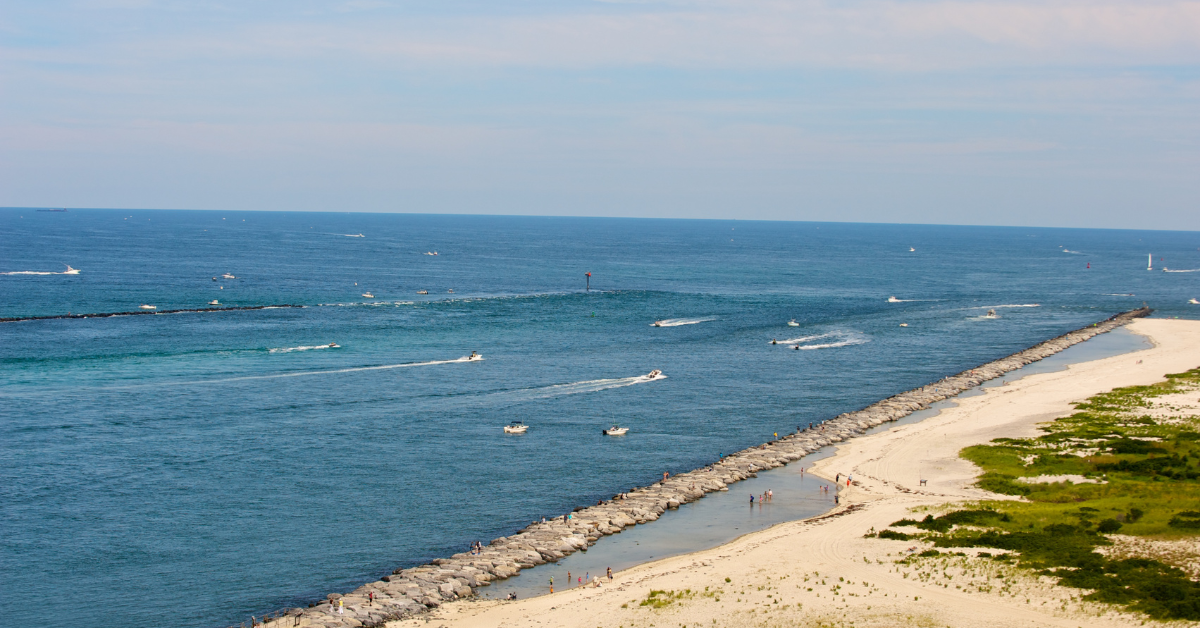 Aerial view of Cape May Point inlet with boats, stone jetty, and sandy beach near West Cape May vacation rentals on the Jersey Shore