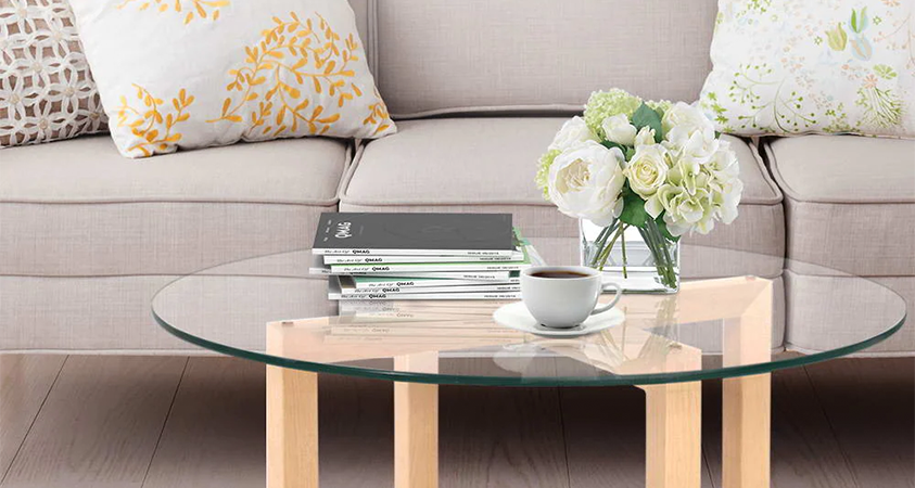 An Artiss Xeni coffee table dressed with a stack of magazines, a cup of coffee and a vase of white flowers.