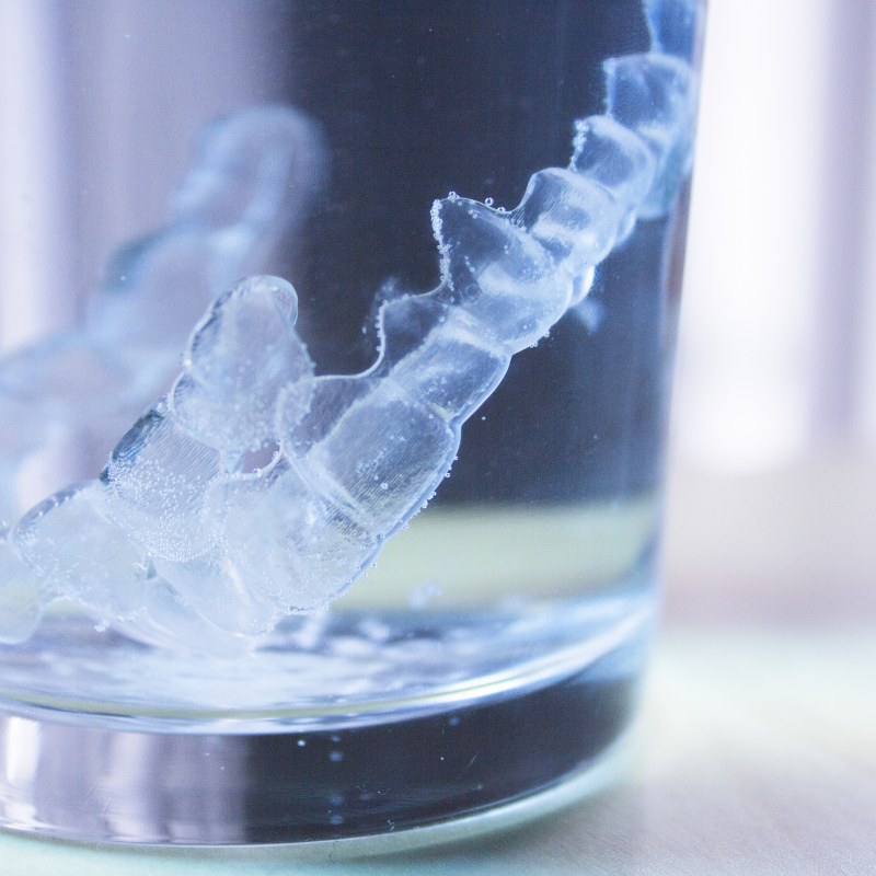 Image demonstrating the process of cleaning clear retainers during Invisalign treatment.