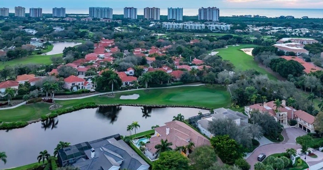 The image depicts a luxurious resort-style pool area surrounded by palm trees and elegant cabanas, creating an inviting atmosphere for relaxation and leisure. This stunning setting is reminiscent of the exclusive beachfront communities found in Pelican Bay, Naples, offering a perfect escape for those seeking refined luxury.