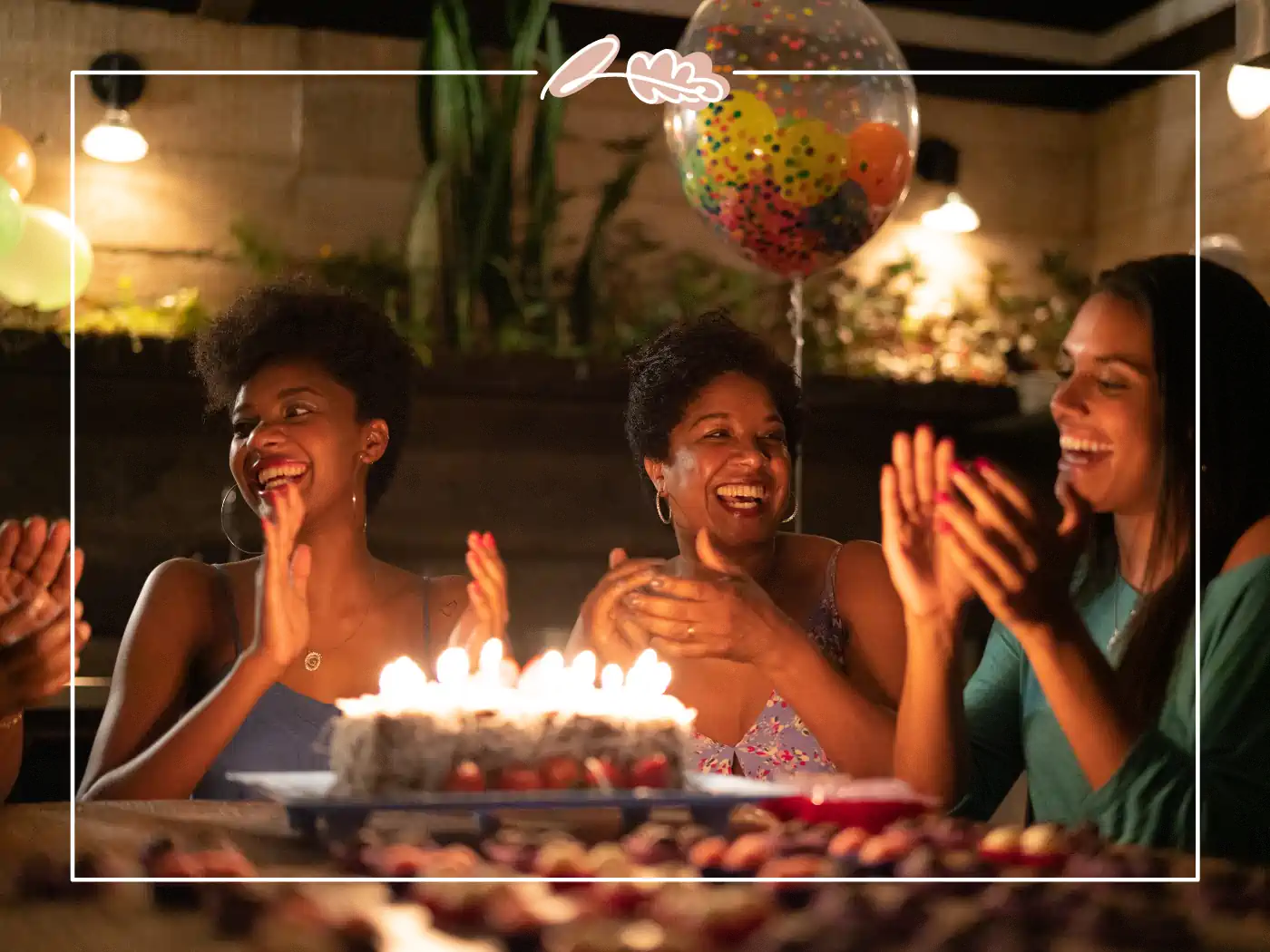 Three women enjoying a birthday celebration with cake and balloons at a cosy indoor party. Fabulous Flowers and Gifts.