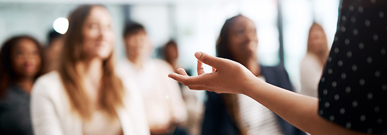 A person holding a sharing information in front of a group of people