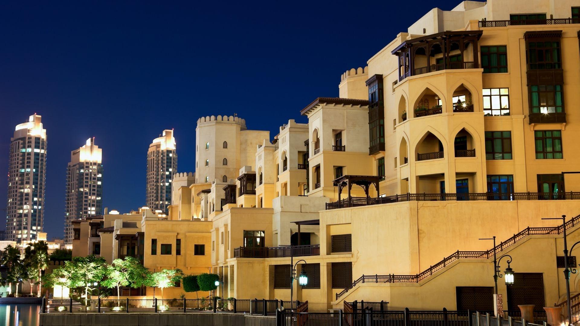 Luxury residential real estate development in Dubai illuminated at night, featuring modern Middle Eastern-inspired architecture and waterfront surroundings.