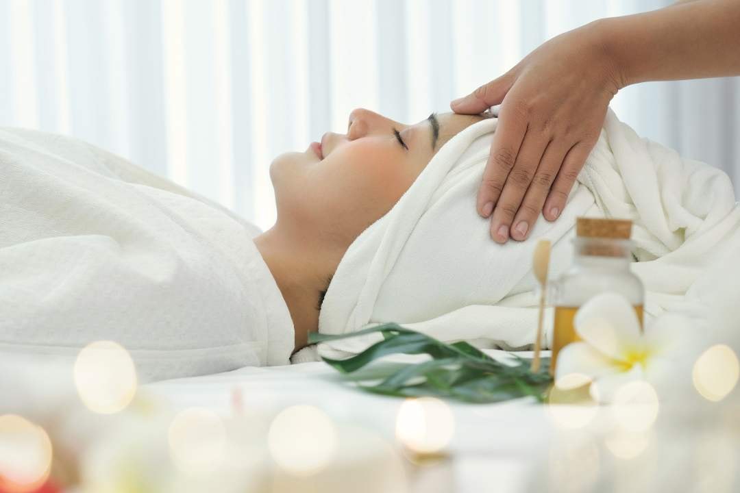 Woman enjoying a facial massage with a towel wrap, creating a calm, rejuvenating spa experience.