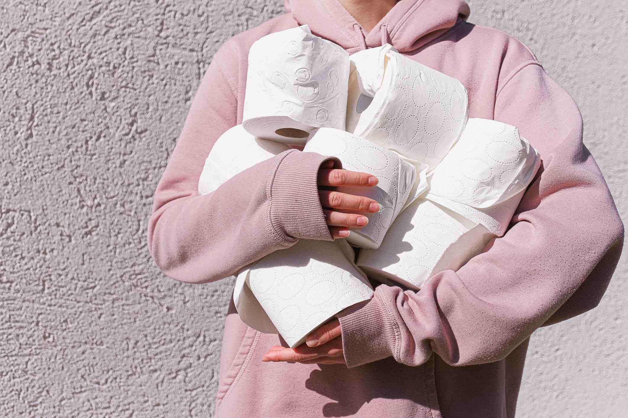 Mulher carregando vários rolos de papel higiénico