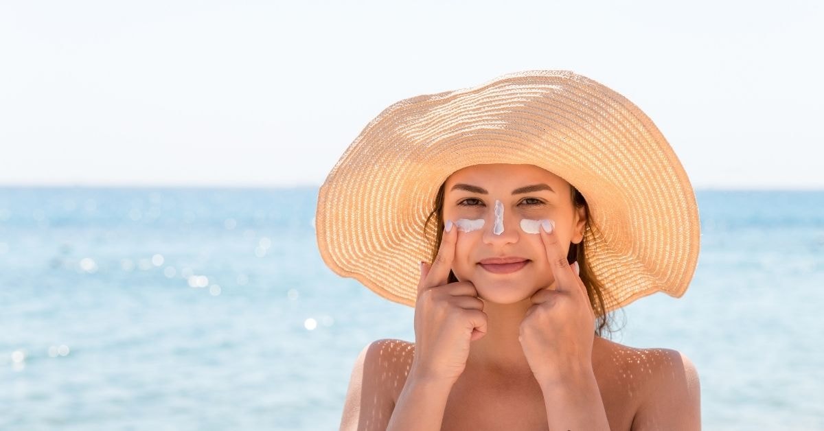 A woman applying sunscreen on the beach, embracing fixed income strategies for financial health.