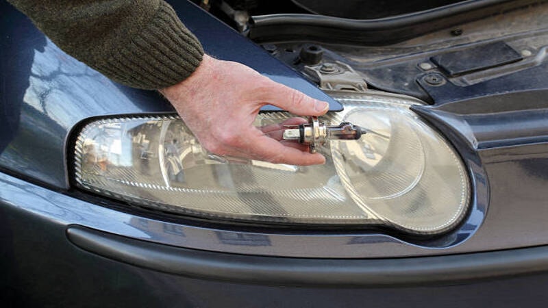 A mechanic fixing a headlight of a car.