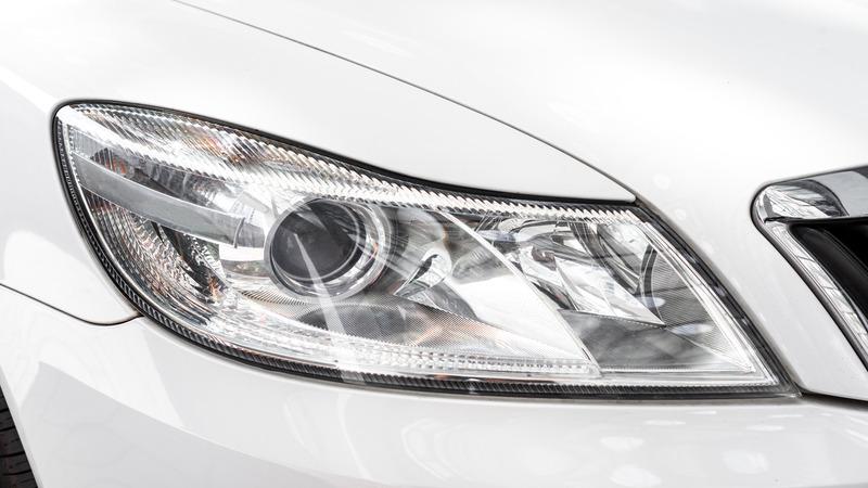 Close-up of a clean, modern car headlight on a white vehicle