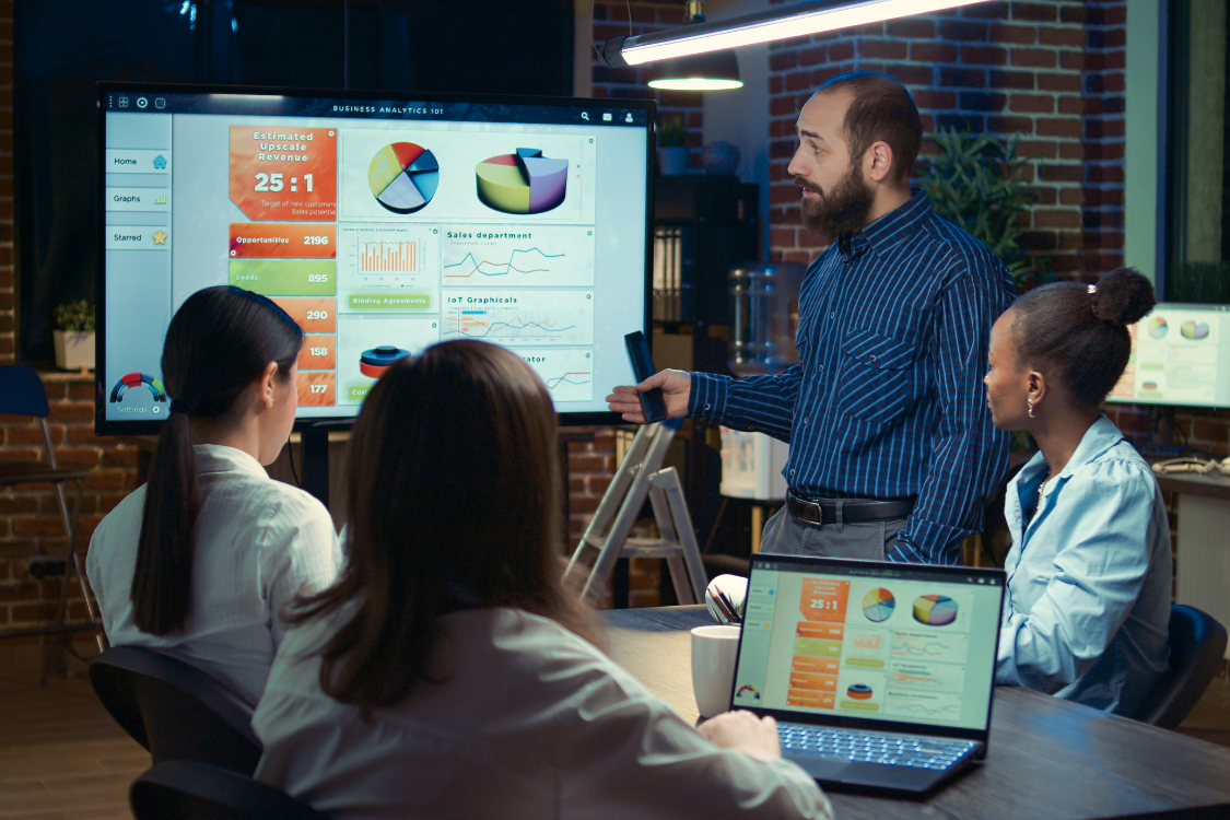 Team watching a business analyst present buyer targeting and revenue data during a strategic outreach session