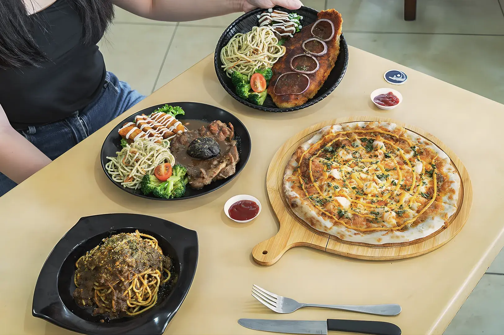 Casual dining spread featuring pizza, pasta, and grilled meat dishes at a Singapore café, highlighting Western fusion cuisine with fresh vegetables and sauces.