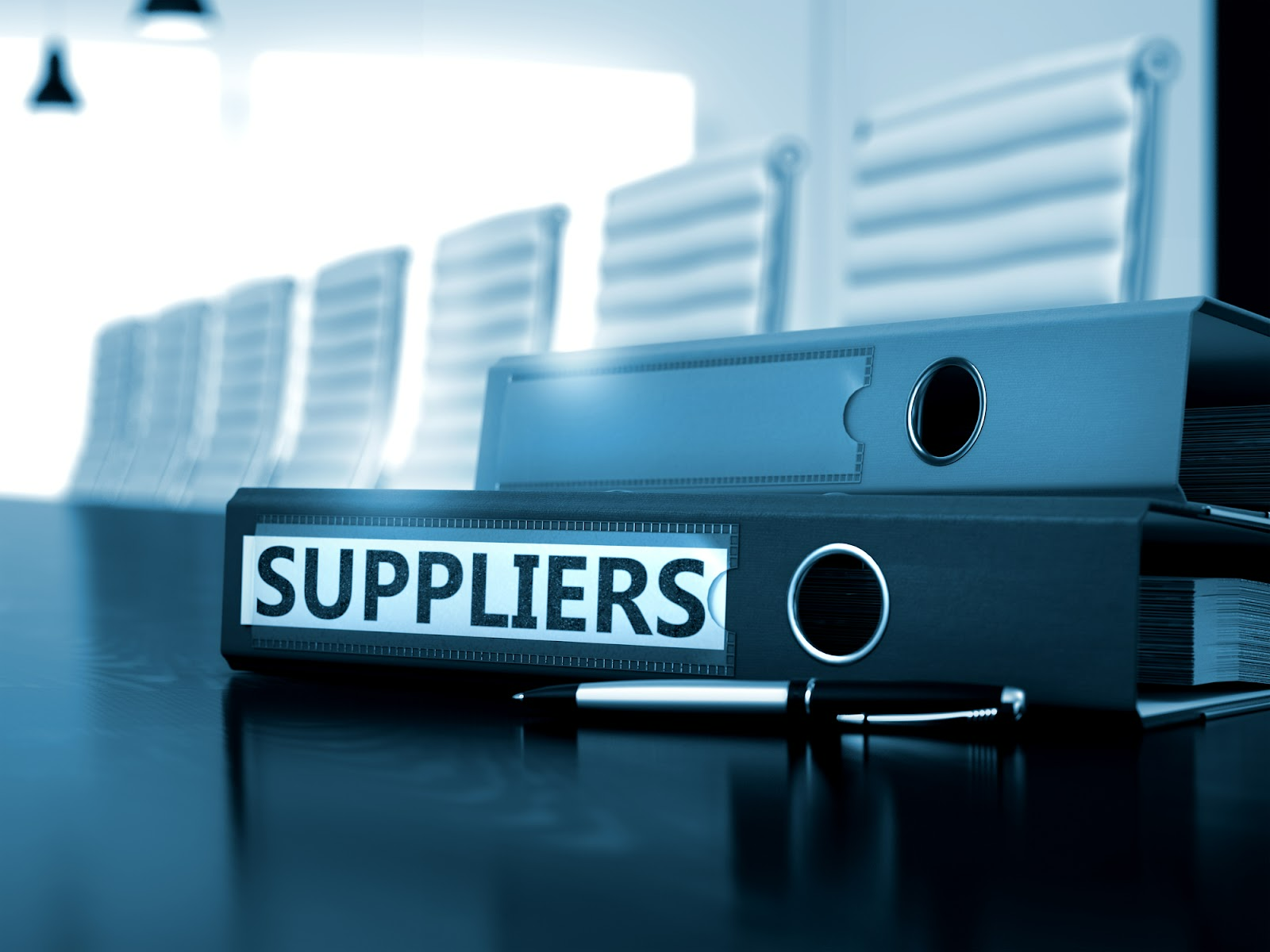 A notebook labeled “suppliers” sits on an office table.