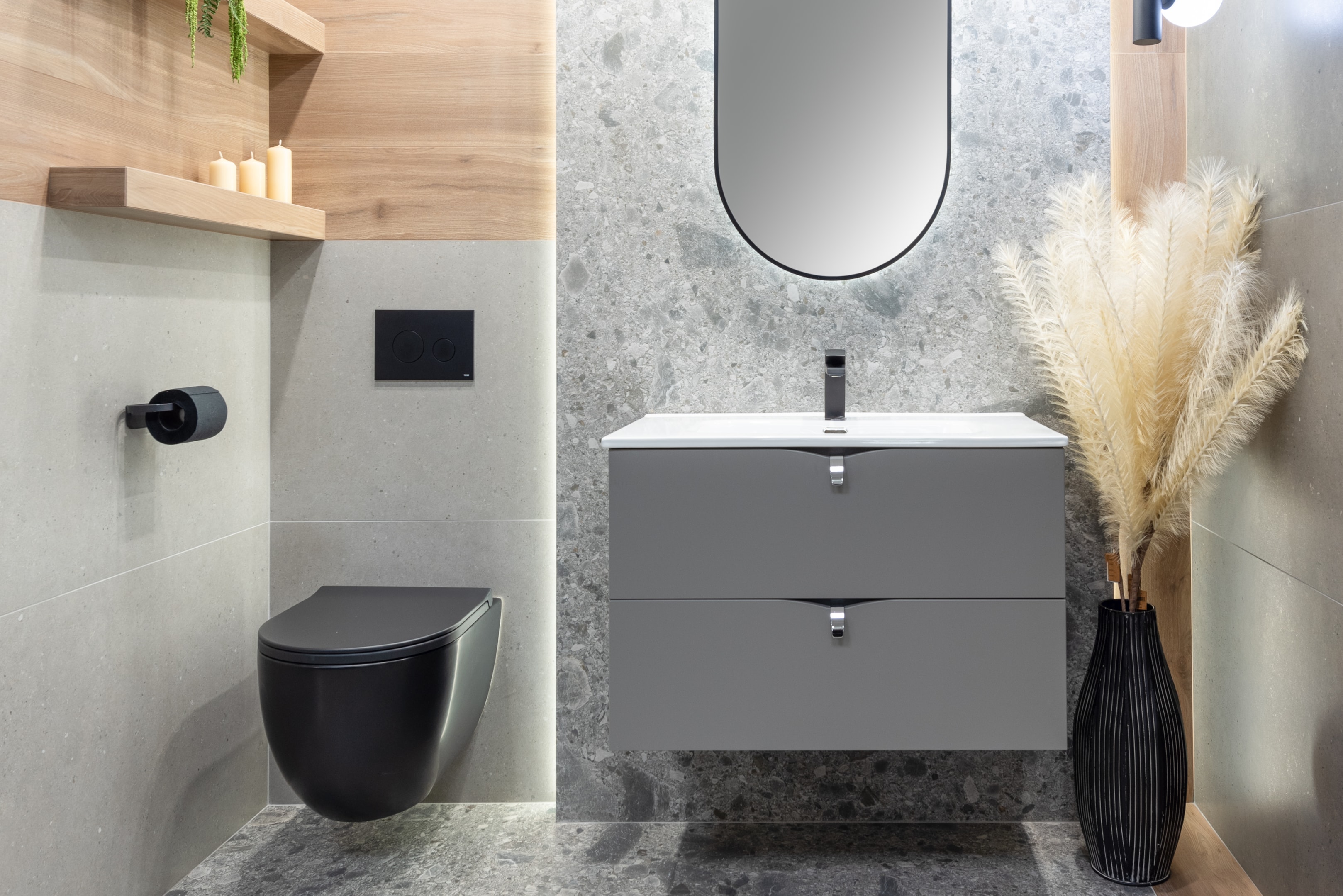 Nowoczesna mała łazienka z szarymi płytkami, czarną toaletą i podwieszaną szafką podumywalkową