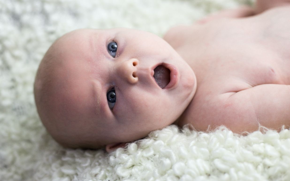 young baby with blue eyes and yawning
