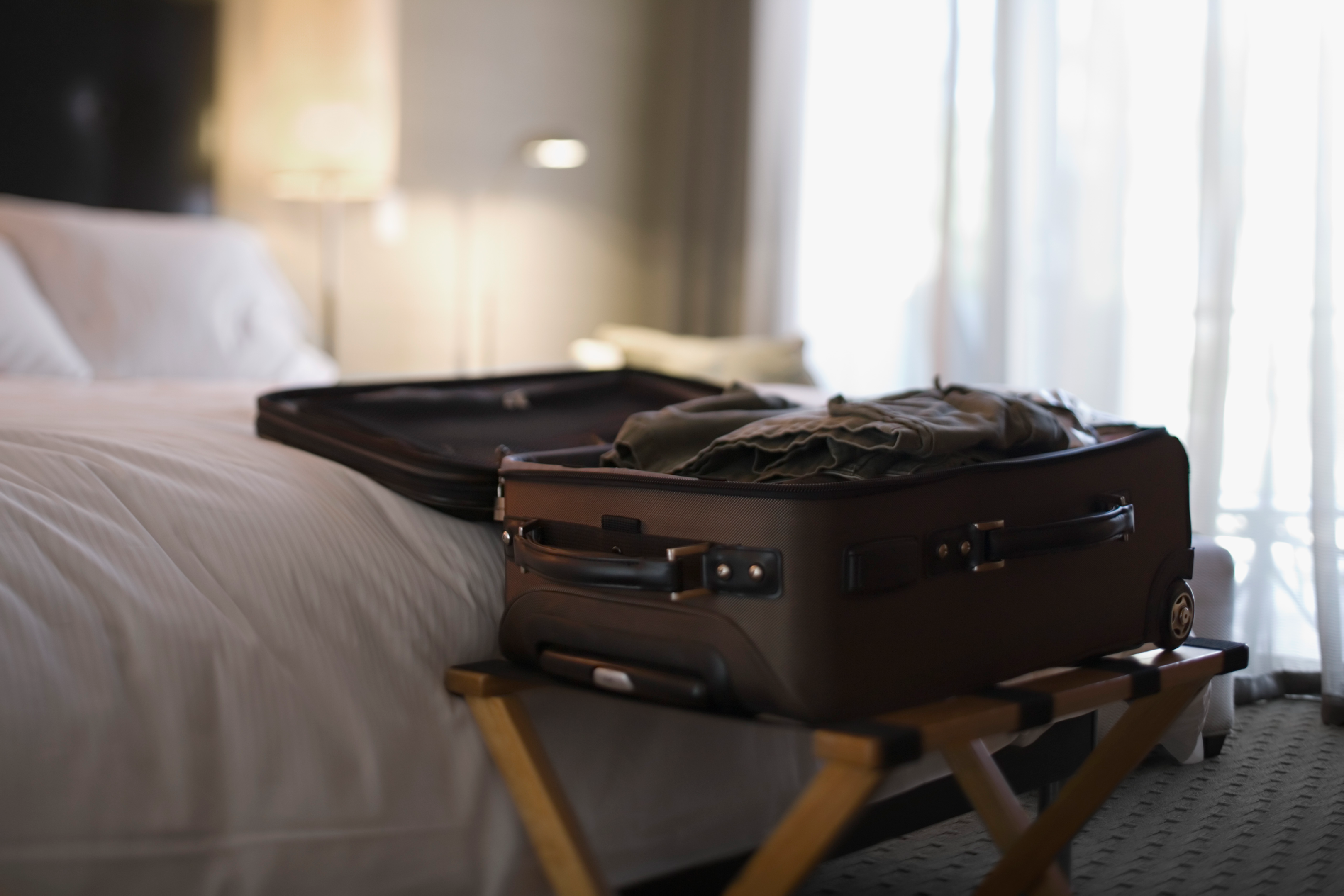 Small guest bedroom with a double duty luggage holder to provide a comfortable space and extra room 