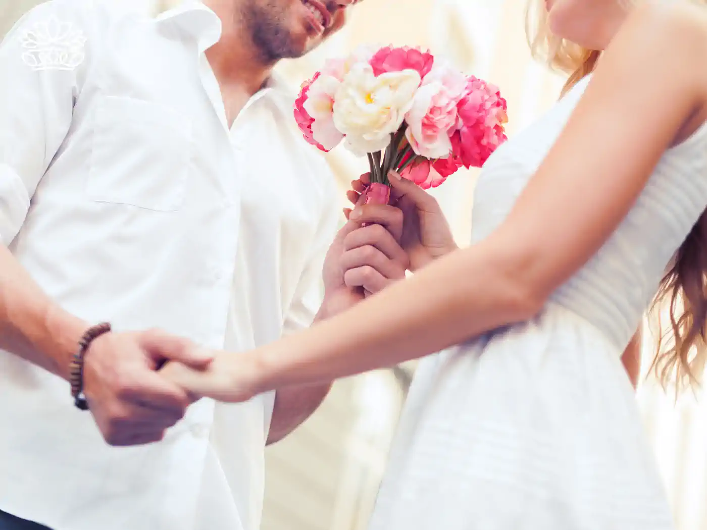 A man holds a woman's hand and presents her with a bouquet of vibrant pink and white flowers, capturing a romantic and intimate moment. Fabulous Flowers and Gifts delivered with heart. Valentine's Day Flowers.