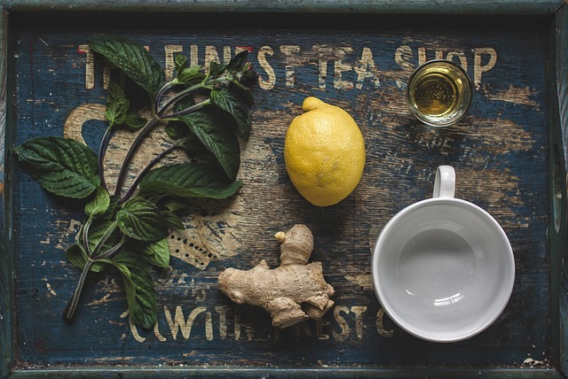 An image of a tea cup, honey, lemon, and ginger on a serving board. 