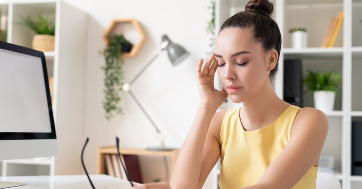 Concerned woman in yellow dress holding her head, considering hiring a tax fraud attorney.