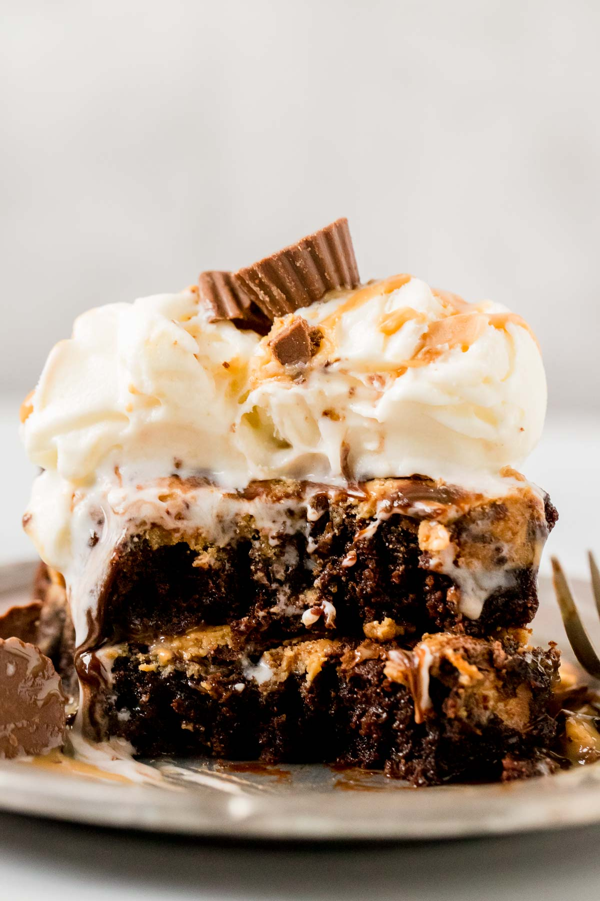 two peanut butter swirl brownies topped with vanilla ice cream and a peanut butter cup