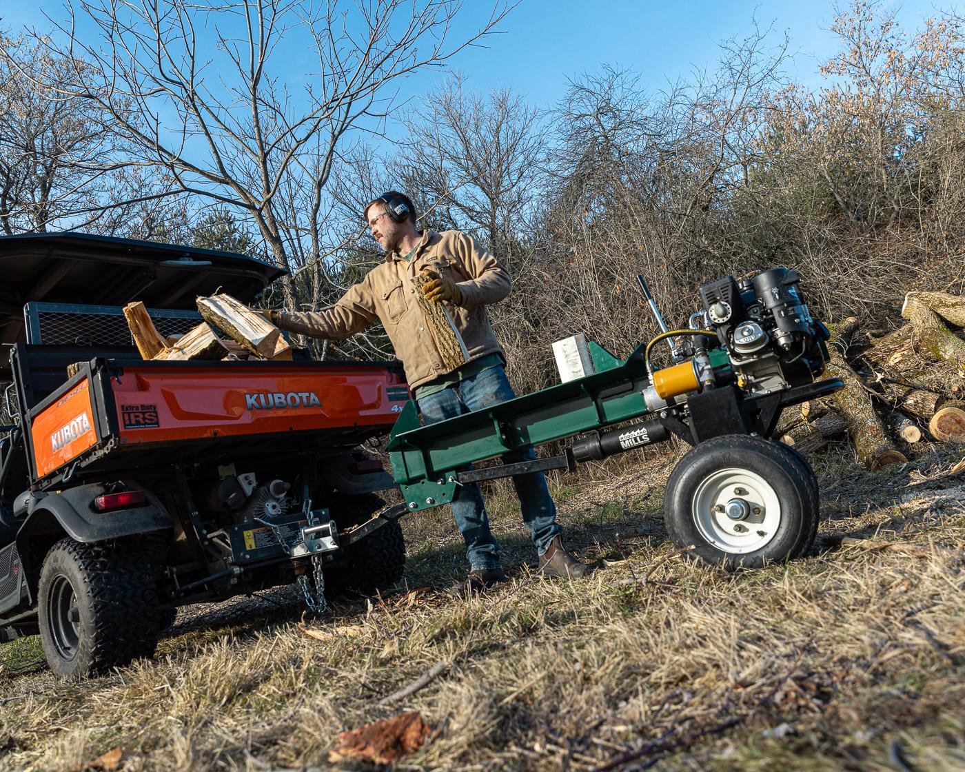 A man tossing firewood into his tractor with a Woodland Mills log splitter attached. 