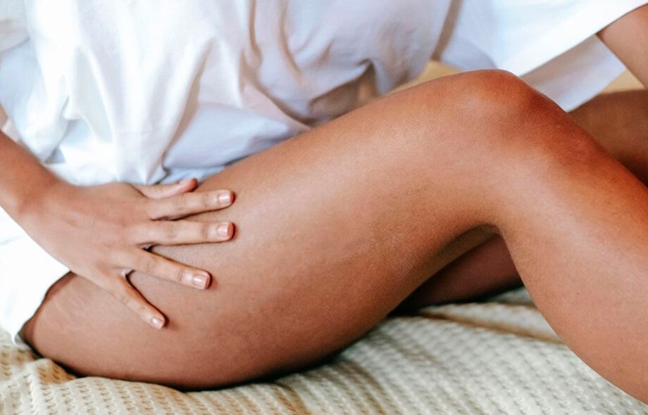 Primo piano di mano di donna controlla la presenza di cellulite sulla coscia destra