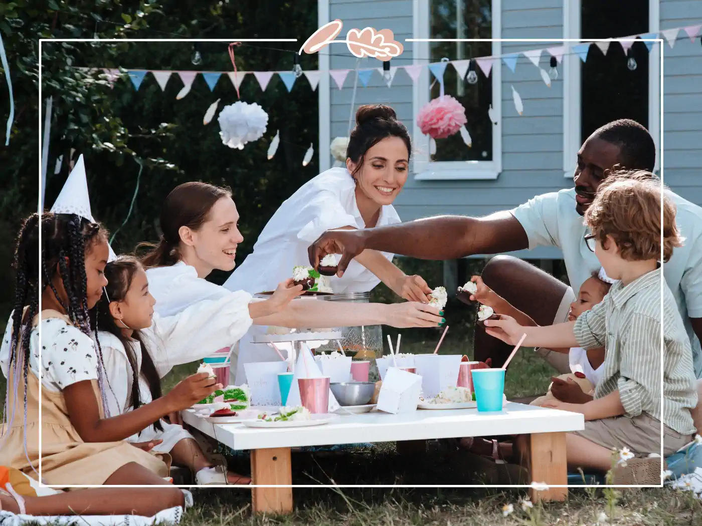 Children and adults celebrating a birthday outdoors with a picnic-style party and colourful decorations. Fabulous Flowers and Gifts.