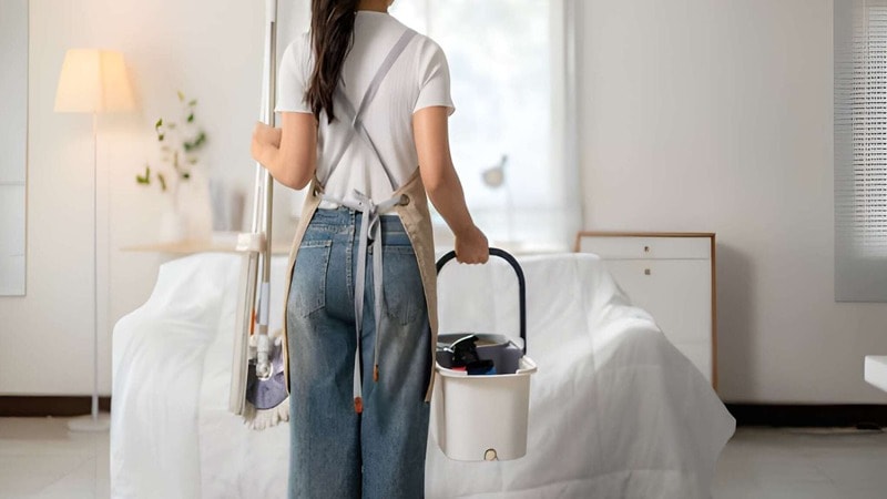 staff holding mop and bucket in a guest room