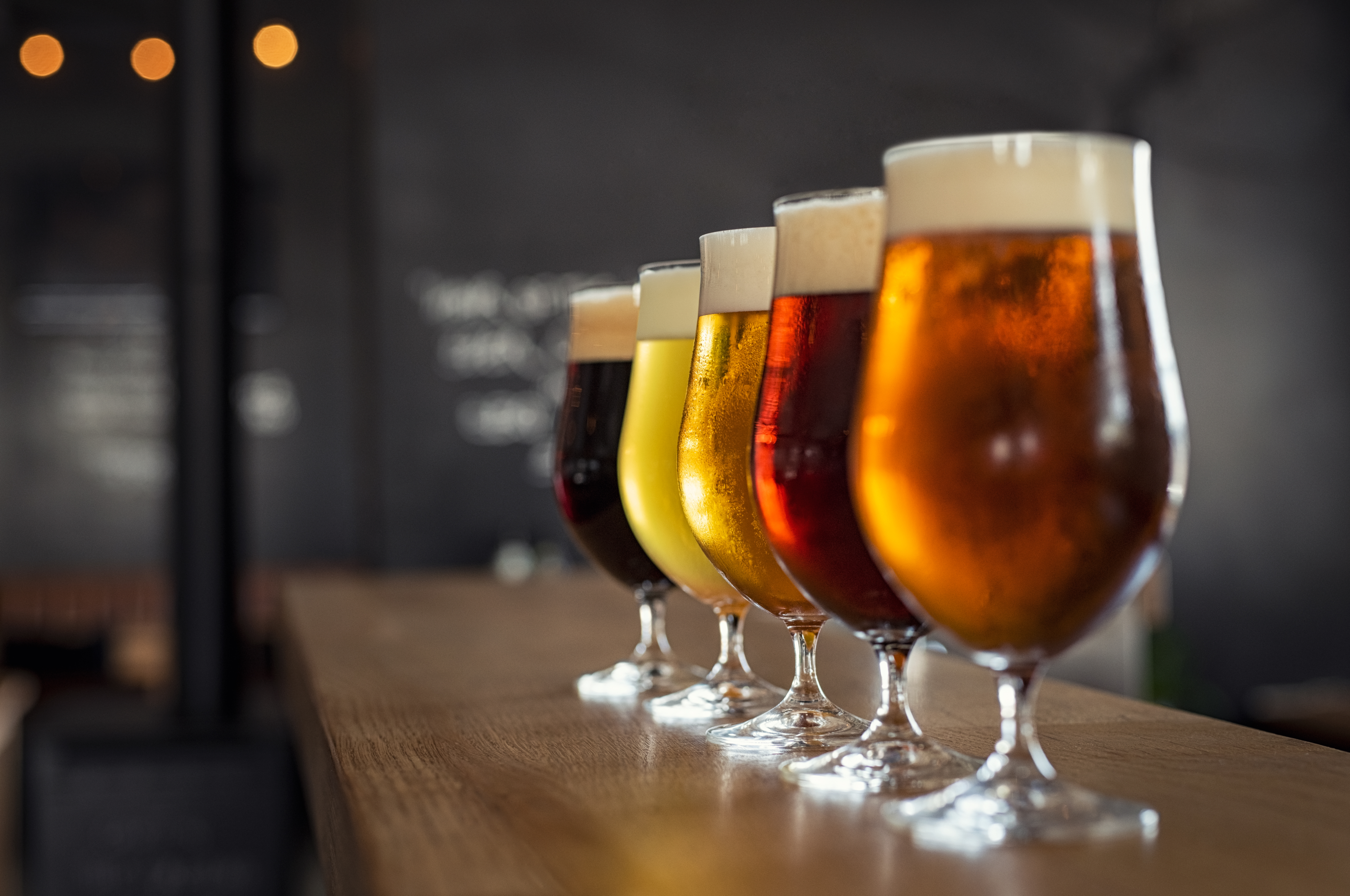 a beer flight in tall beer glasses ranging from light to dark on a wooden counter at Charleston South Carolina breweries