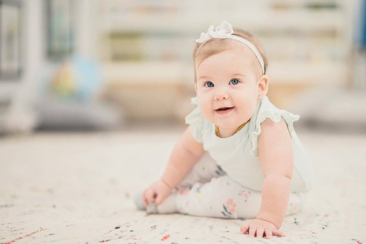 Baby girl sitting up using arms for balance. Poppyseed Play