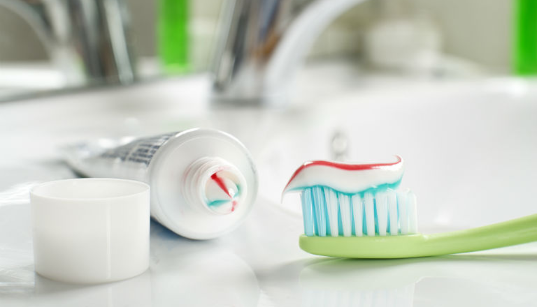 Fluor – Hvorfor det er viktig for sterke og friske tenner 20 "Grønn tannbørste med tannkrem foran åpen tube på baderomsbenk.