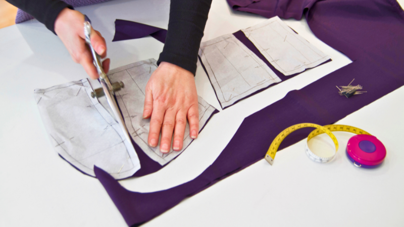 A closer up image of a person using a scissors to cut fabric