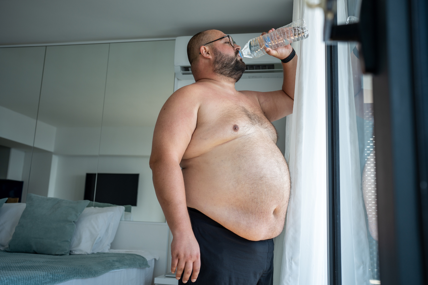 Heavy set man drinking water.