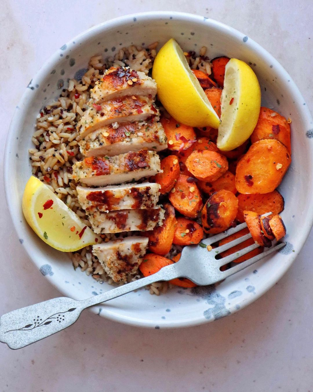 Grilled chicken, carrots, and lemon wedges on a bed of Proper Good's Brown Rice & Quinoa Blend