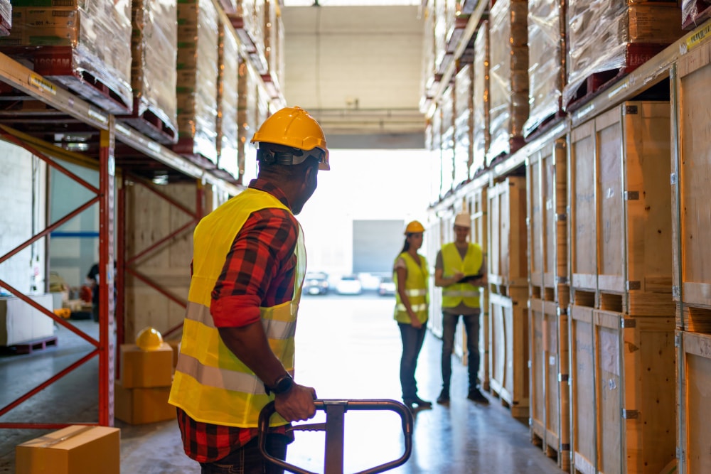 Back view of a team working in factory warehouse backed by a business phone system with voicemail transcription helping them ensure customer expectations are met..