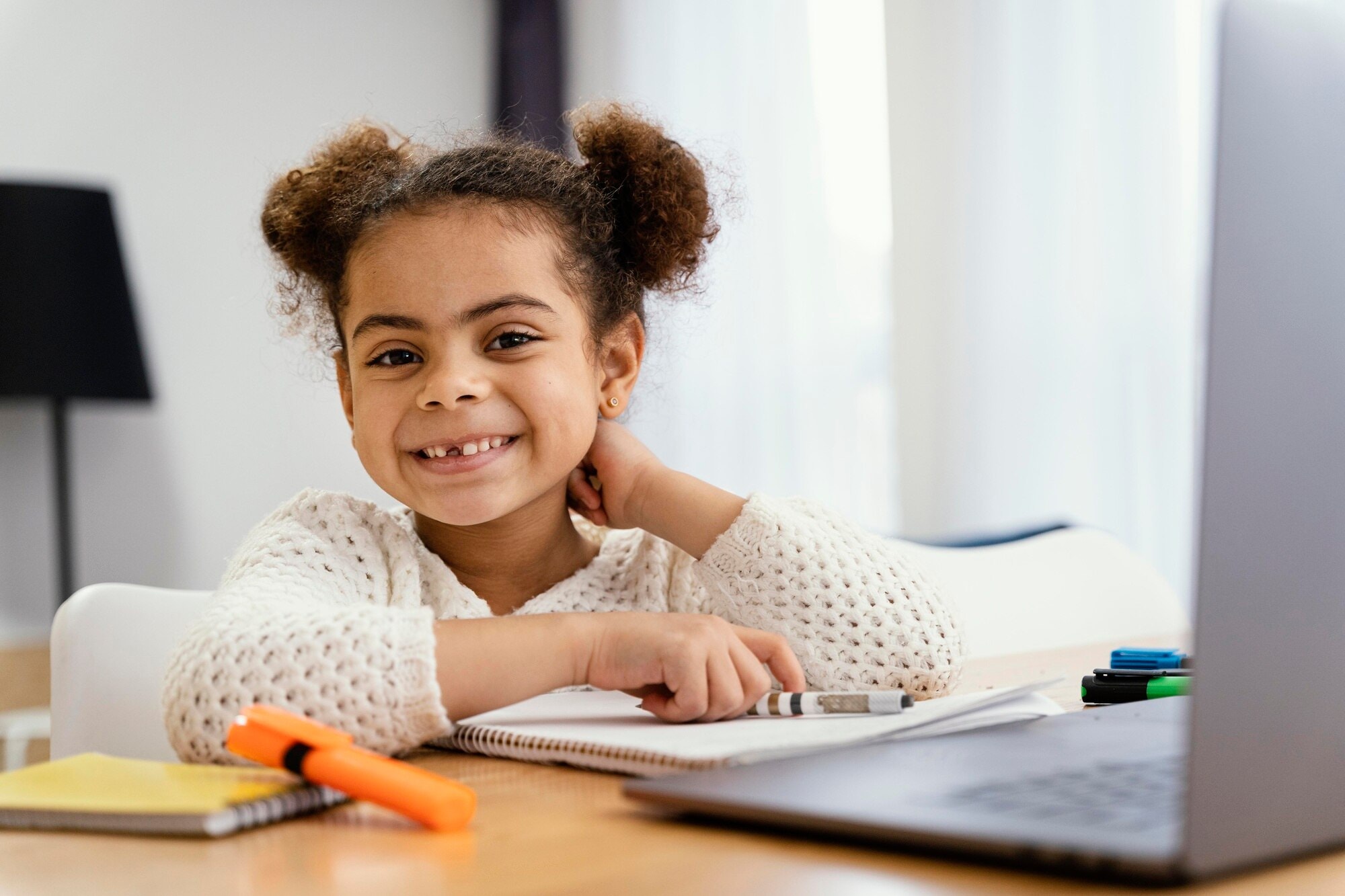 Smiling girl in school learning with notebook and laptop