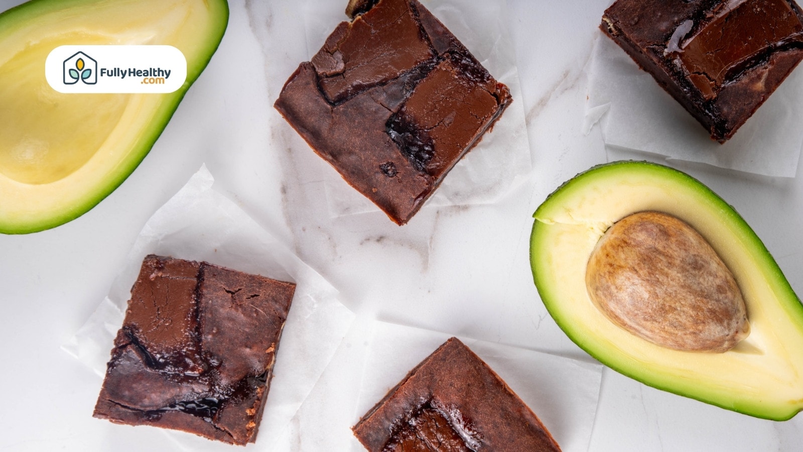 Chocolate brownies on parchment paper with fresh halved avocado beside