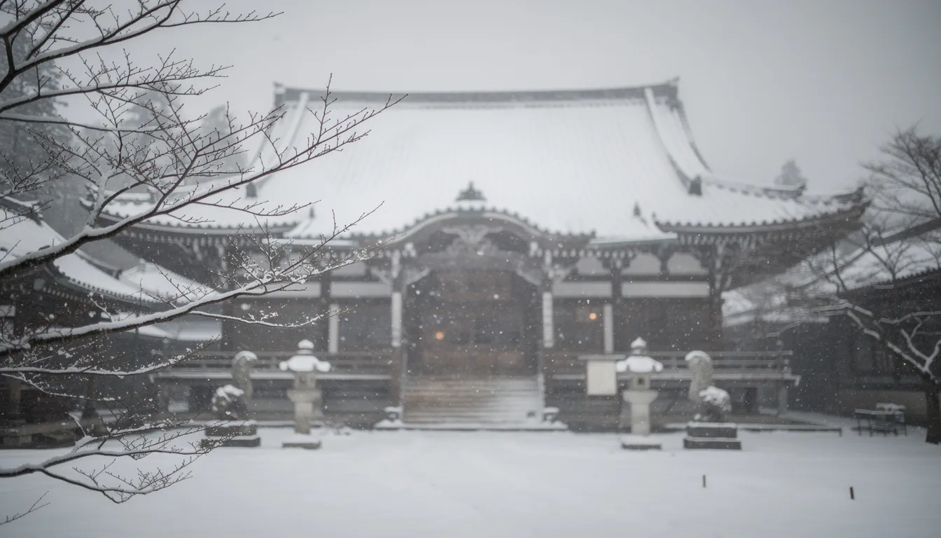 La imagen muestra un templo japonés tradicional parcialmente oculto por una suave caída de nieve, con ramas de árboles desnudos enmarcando la escena contra un cielo gris apagado. Este paisaje sereno captura la esencia del invierno en Japón, recordando las obras de Kawase Hasui, conocido por sus hermosos grabados en madera y escenas de nieve.