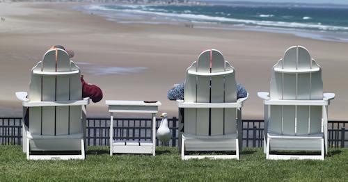 Visitors sitting in Adirondack chairs, waiting for the sunset, in Ogunquit, Maine