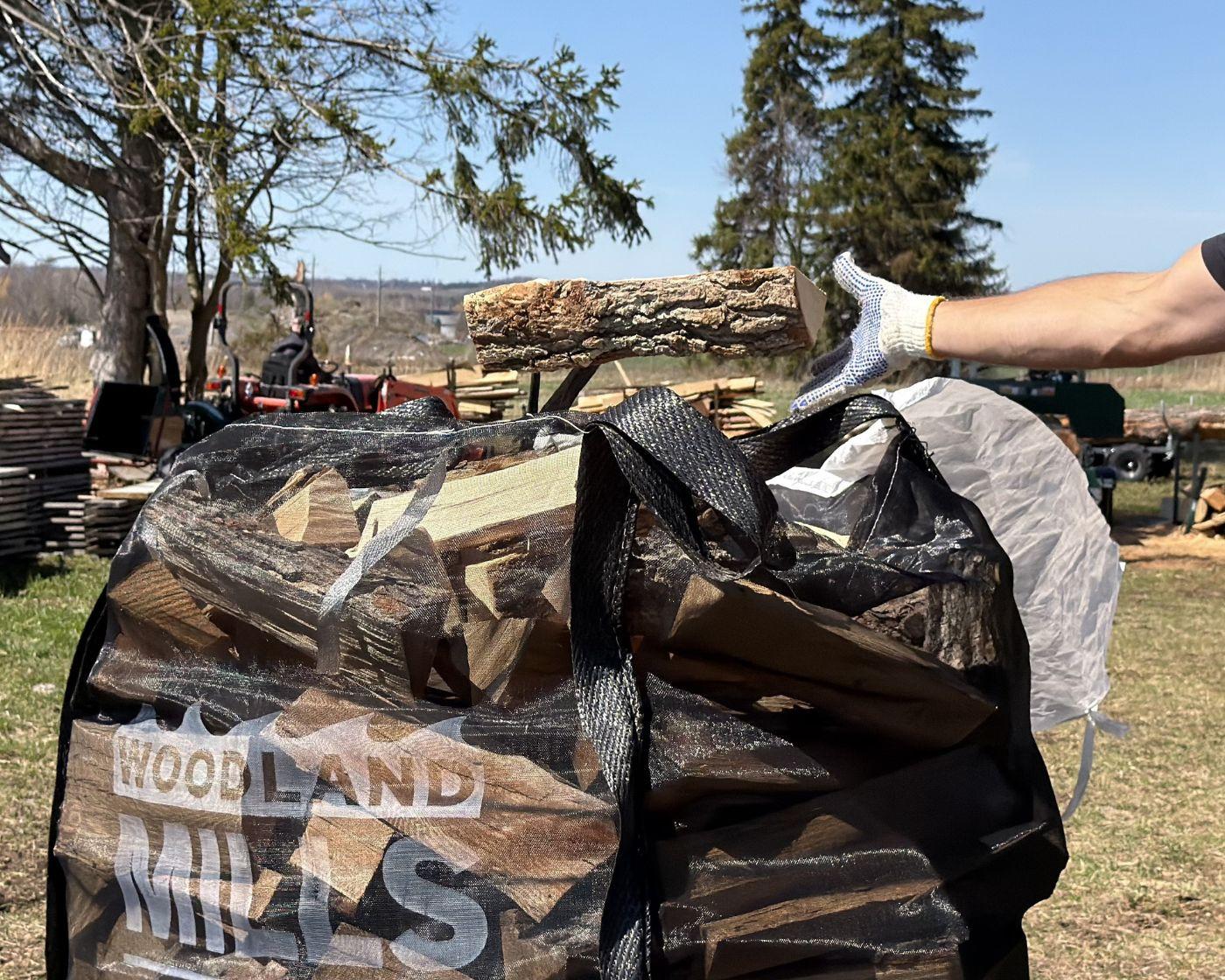 A man tossing firewood into a Woodland Mills bulk firewood bag.