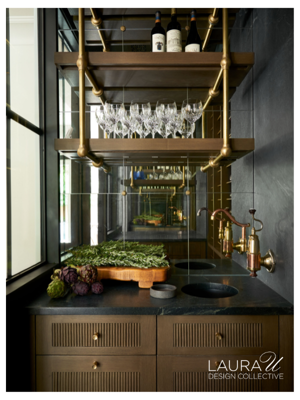 Brass shelving with integrated LED lighting illuminates wine bottles and stemware inside the Huntwick Forest wine cellar.