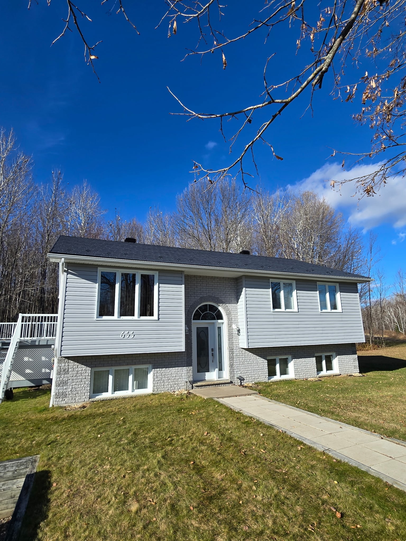 A home newly installed metal roof features a big yard and a driveway, creating an inviting outdoor space.